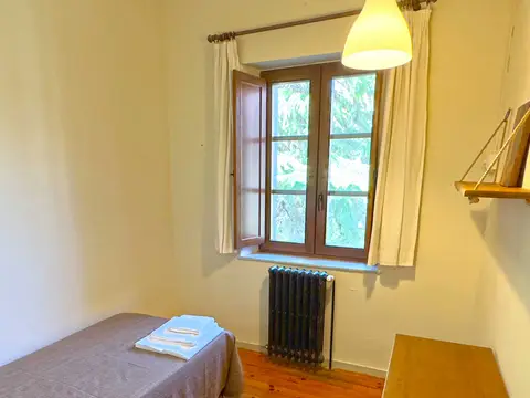 habitación individual del albergue, con cama, mesa y ventana al patio