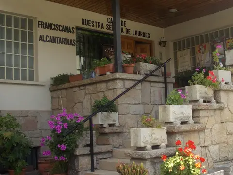 porche de entrada de la casa, con la rotulación «Casa de Franciscanas Nuestra Señora de Lourdes Alcantarinas»