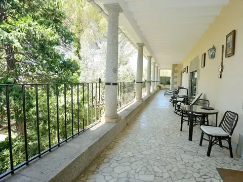 galería porticada de la casa, con mesas y sillas al aire libre