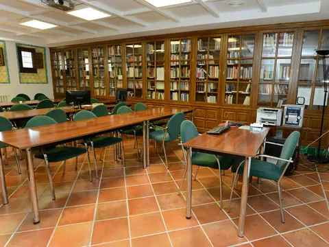 aula-biblioteca de la casa, con mesas de estudio y estanterías