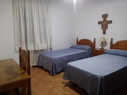 habitación de huéspedes con dos camas individuales y crucifijo de San Damián
