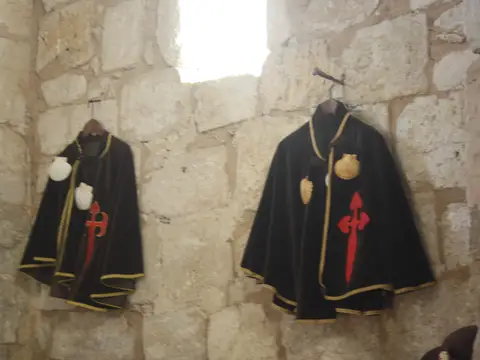 interior de piedra de la ermita, con las capas de los hospitaleros de la cofradía colgadas