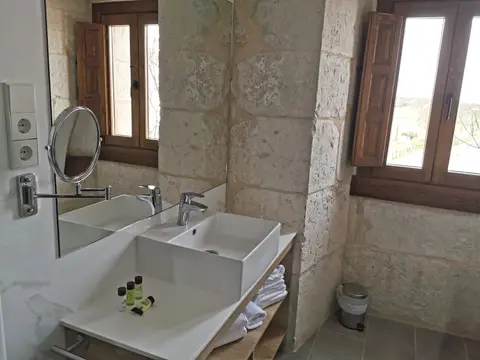 baño de habitación, con el muro de piedra del monasterio