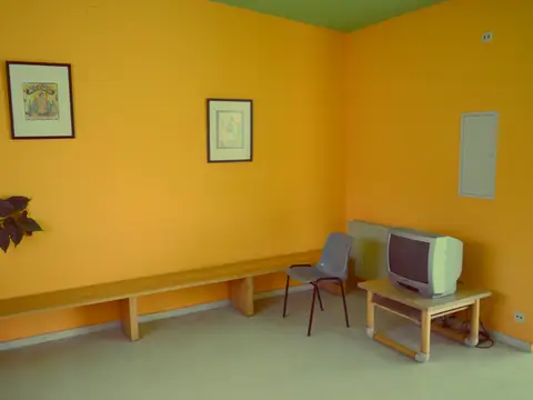 sala de estar de los peregrinos, con banco corrido y televisor