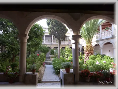 claustro ajardinado con fuente y galeria de arcos