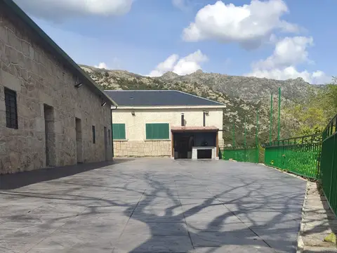 patio pavimentado de la instalación con el edificio de piedra y la sierra al fondo