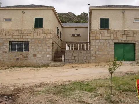 edificio principal de la instalación de Mataelpino, de mampostería y dos plantas, con la escalera exterior y el portón verde