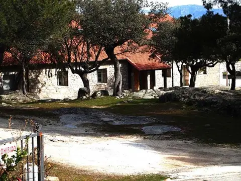 otro de los edificios de la finca entre los pinos, con el porche de piedra y la sierra al fondo