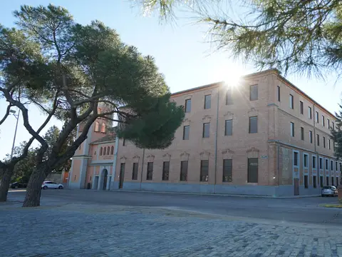 fachada del edificio de la casa, con la explanada y los pinos