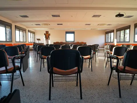 la sala «Hermano Sol», con las sillas dispuestas y las ventanas al bosque