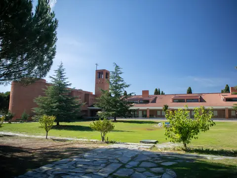vista del conjunto de la casa desde el jardín, con los pabellones largos de ladrillo y el arbolado