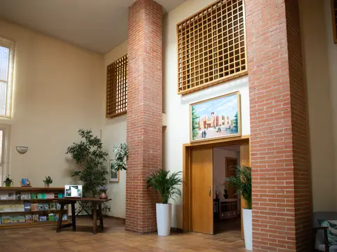 vestíbulo de acogida, con los pilares de ladrillo visto y la entrada a la casa