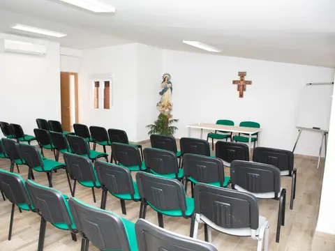 sala de reuniones con las sillas en filas y una cruz en la pared