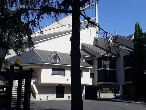 el edificio de la casa visto desde la calle, entre los árboles