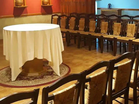 sala de reuniones con mesa redonda y las imágenes de los Sagrados Corazones al fondo