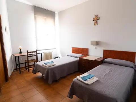 habitación doble con dos camas, mesa de trabajo y crucifijo