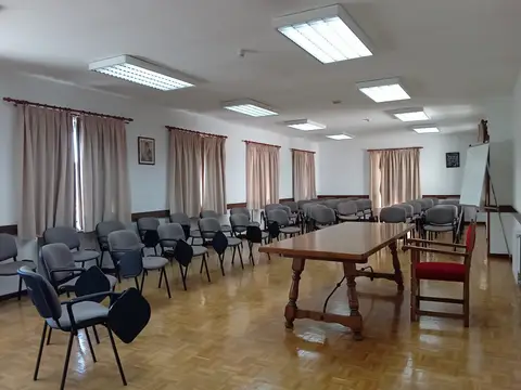 sala de reuniones grande con sillas de pala y mesa, con crucifijo en la pared