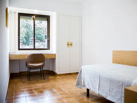 habitación con cama, mesa de escritorio y ventana