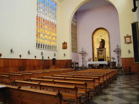 capilla de la casa, con los bancos de madera y las vidrieras