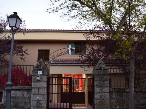 entrada de la casa desde la calle, con la verja y el porche iluminado