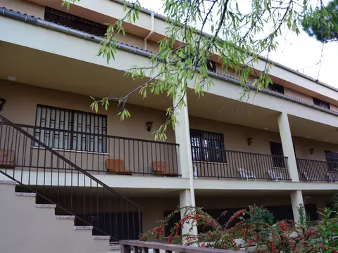 el edificio de la casa con la galería y la escalera exterior, entre la vegetación
