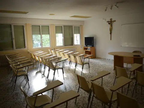 sala de conferencias con sillas de pala y crucifijo