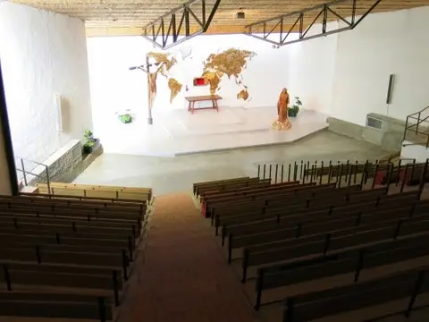 capilla grande de la Casa de Espiritualidad, con el mural del mundo al fondo y los bancos en filas
