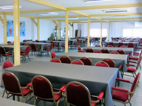 comedor general con las mesas largas y las sillas rojas