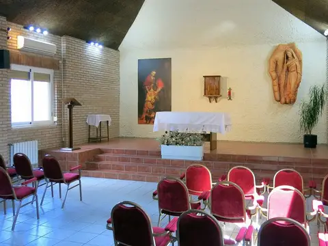 capilla de uno de los pabellones, con el altar sobre la tarima y las sillas rojas