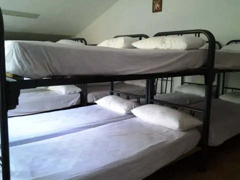 habitación del albergue, con literas metálicas bajo el techo abuhardillado