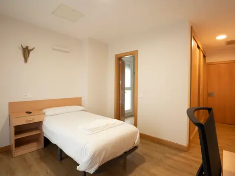 habitación individual con cama, escritorio y armario