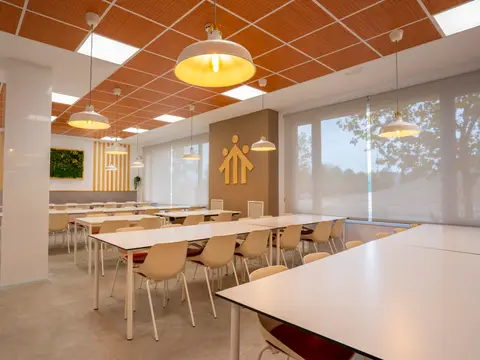 sala multiusos y comedor, con las mesas corridas bajo el techo de madera
