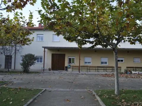 fachada del edificio principal de la casa, con la entrada y los árboles delante