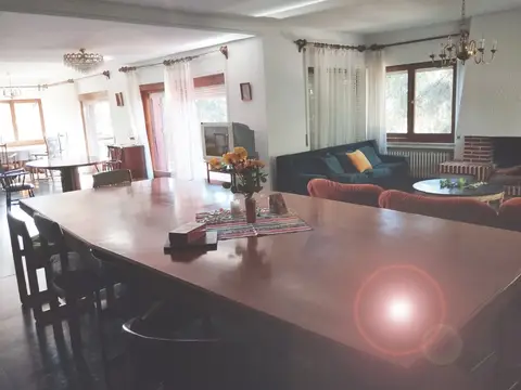 salón-comedor de la vivienda, con la mesa larga, la chimenea y los ventanales al jardín