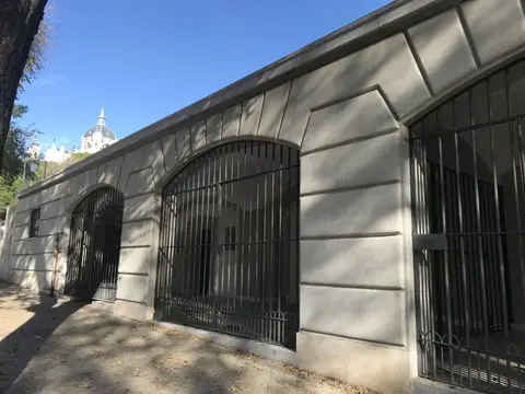 fachada del Centro Juvenil Santa María de la Cabeza, con la galería de arcos enrejados y la cúpula de la Almudena al fondo