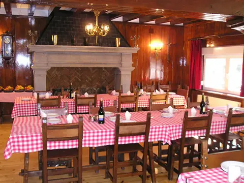 comedor rústico con vigas de madera, chimenea de piedra y mesas puestas