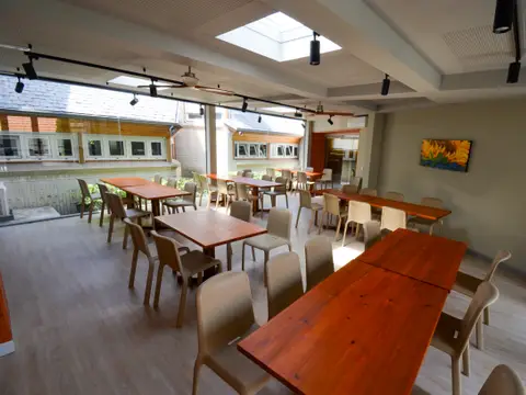 comedor con las mesas corridas de madera y los ventanales