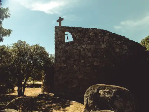 la capilla de piedra de la finca, con la espadaña y la cruz, entre los berruecos de granito