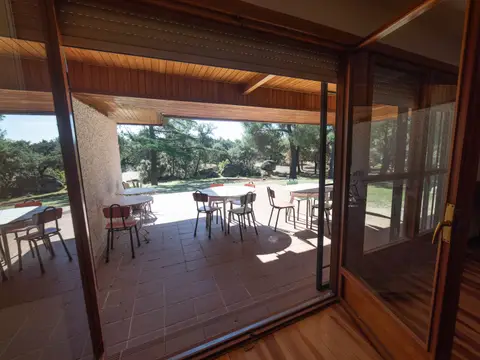 comedor acristalado de la casa, con las mesas y la vista al campo