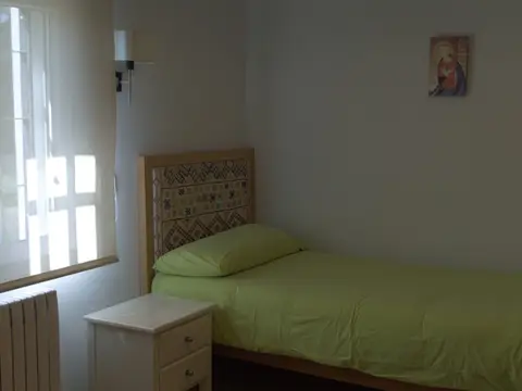 habitación individual con cama, mesilla y ventana al jardín