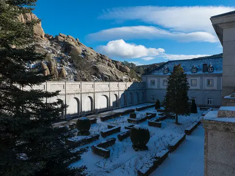 vista exterior de la abadía benedictina bajo la roca del Valle de los Caídos, con el claustro y el jardín nevado
