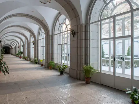 galería acristalada del claustro, con las plantas y la vista al jardín