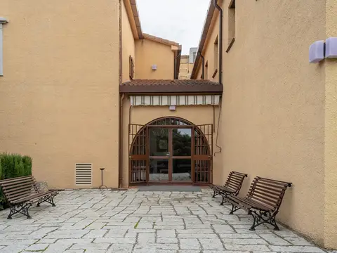 entrada principal de la casa, con el patio empedrado y los bancos