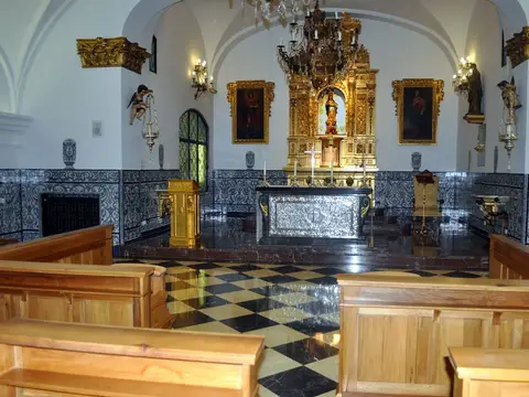oratorio de la casa, con el retablo dorado, los bancos y el suelo ajedrezado