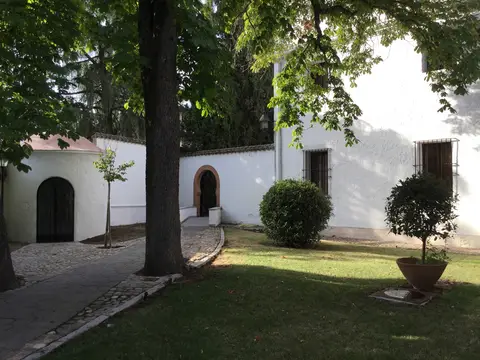 pabellón bajo encalado de la finca, con el porche y el césped delante