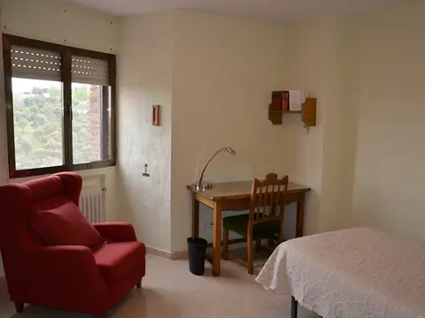 habitación individual con cama, butaca y escritorio