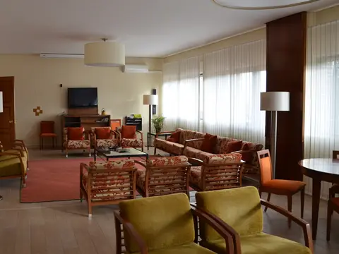 cuarto de estar con sillones, alfombras y los ventanales al campo