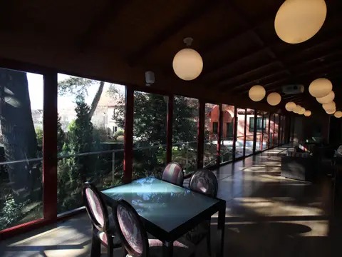 galería acristalada de la casa, con las lámparas esféricas y las mesas junto a los ventanales