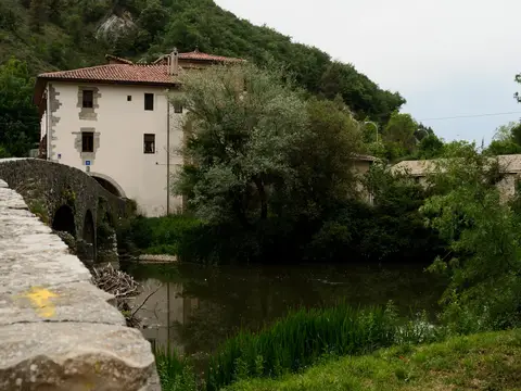 el puente del peregrino y el edificio de la basílica-albergue desde la orilla