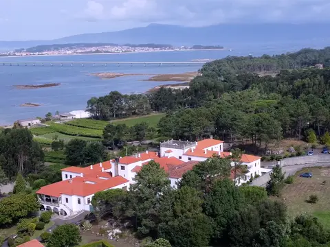 vista aérea del centro entre el pinar, con la ría de Arousa al fondo